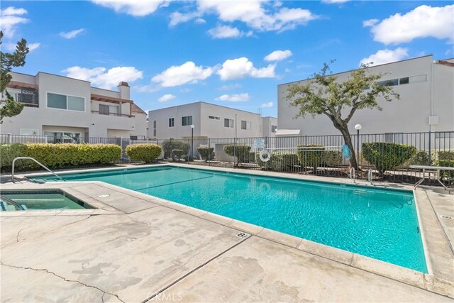 community pool with a sink, a patio, fence, a residential view, and a hot tub