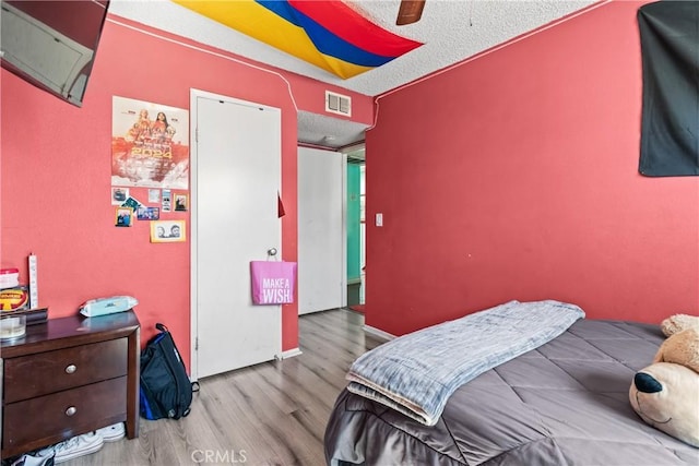 bedroom featuring visible vents, a textured ceiling, wood finished floors, and a ceiling fan