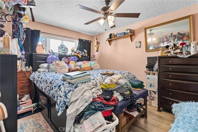 bedroom featuring a textured ceiling, a ceiling fan, and wood finished floors