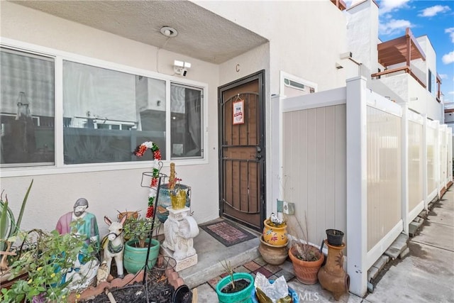 entrance to property with stucco siding and fence