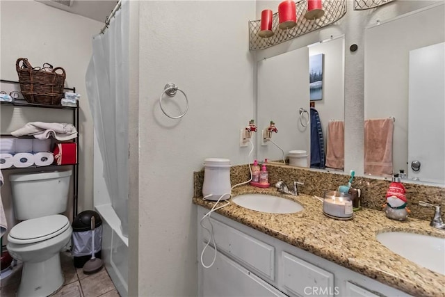 bathroom with double vanity, tile patterned floors, toilet, and a sink