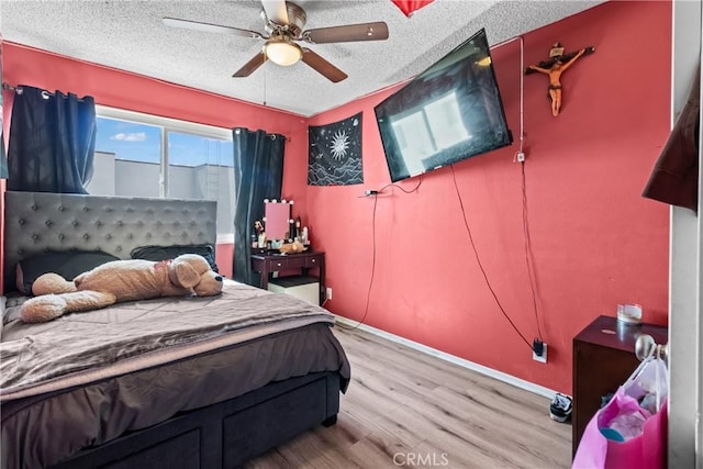 bedroom featuring light wood-style flooring, a ceiling fan, and a textured ceiling