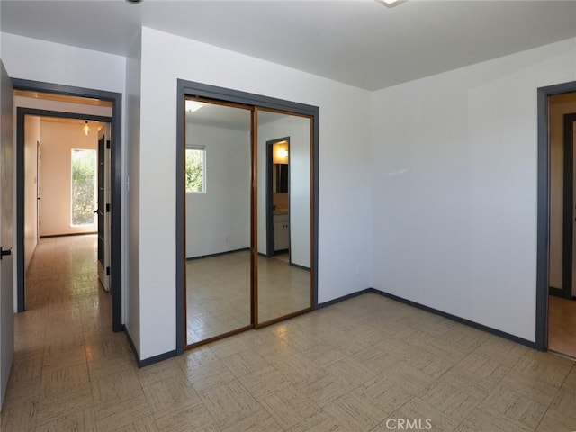 unfurnished bedroom with a closet, light floors, and baseboards