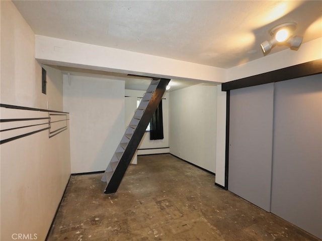 finished basement featuring a baseboard radiator and stairs