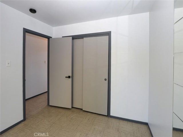 unfurnished bedroom with a closet, baseboards, and light floors