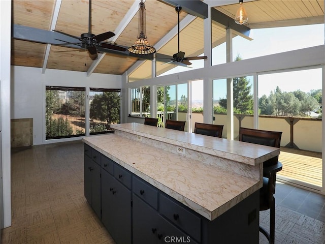 kitchen featuring beam ceiling, open floor plan, a breakfast bar area, light countertops, and wood ceiling