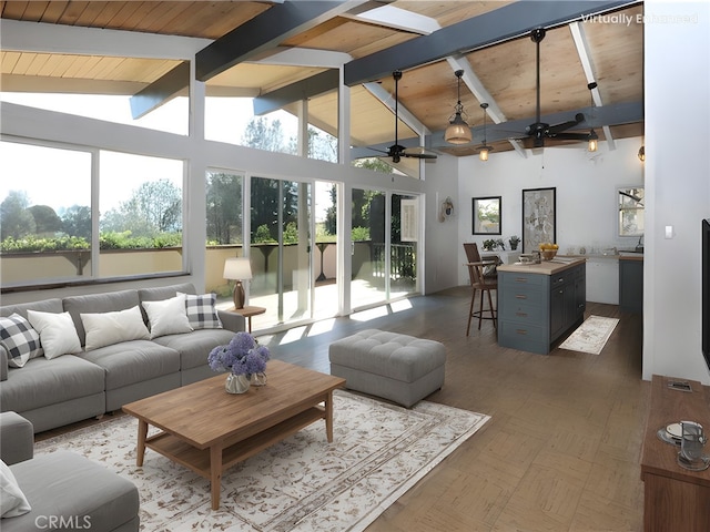 living room featuring beam ceiling, wood ceiling, plenty of natural light, and a ceiling fan