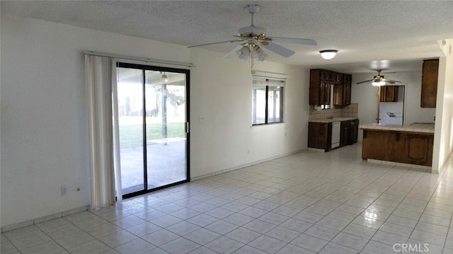 unfurnished living room featuring light tile patterned floors, a ceiling fan, baseboards, and a textured ceiling