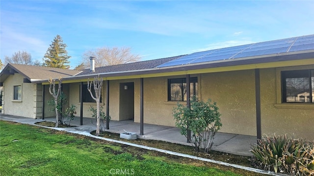 view of front facade featuring stucco siding, a patio, and a front yard