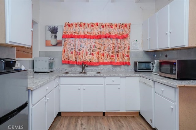 kitchen with white dishwasher, light countertops, white cabinetry, stainless steel microwave, and light wood-type flooring