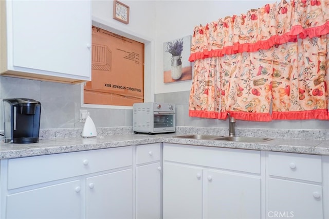 kitchen with a toaster, white cabinets, decorative backsplash, and a sink