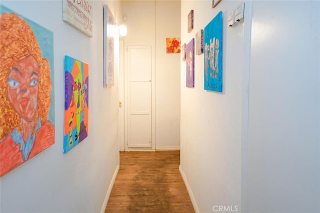 corridor with baseboards and wood finished floors