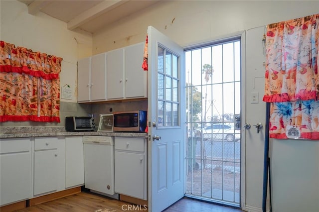 kitchen with stainless steel microwave, wood finished floors, white cabinets, and white dishwasher