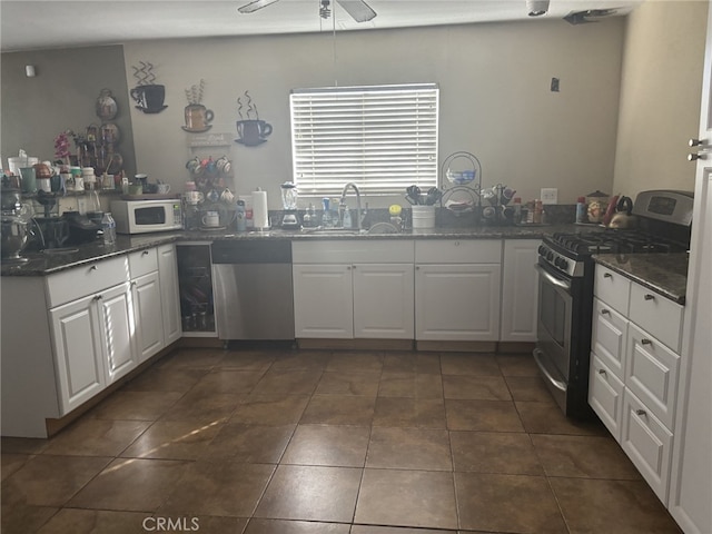 kitchen with white cabinets, dark tile patterned floors, appliances with stainless steel finishes, and a sink