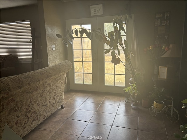 doorway to outside featuring tile patterned flooring, french doors, and a textured wall