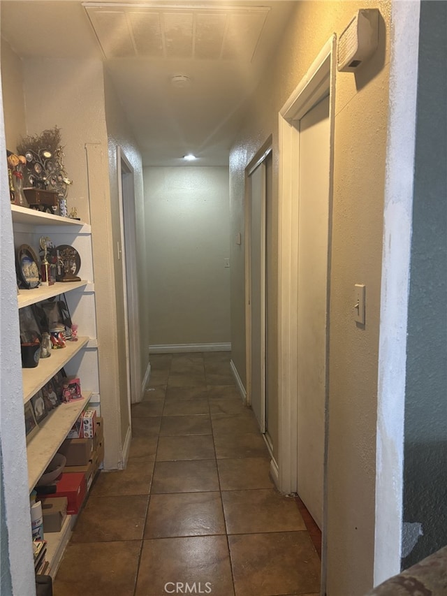 hallway featuring tile patterned floors and baseboards