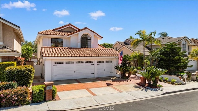 mediterranean / spanish-style home with a tile roof, driveway, and stucco siding