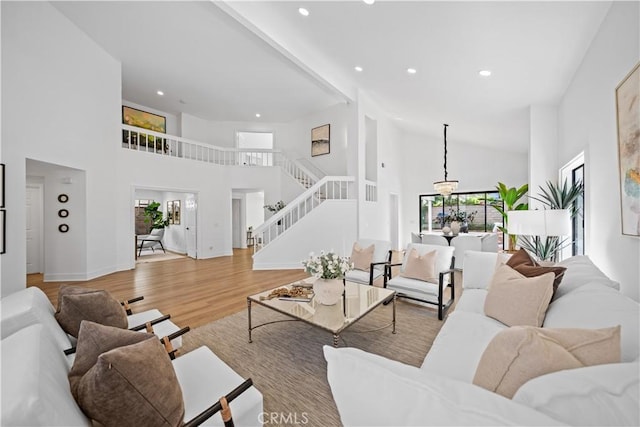 living area with a wealth of natural light, stairs, a high ceiling, and wood finished floors