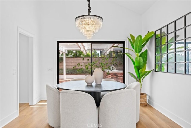 dining room featuring baseboards, light wood-type flooring, and an inviting chandelier