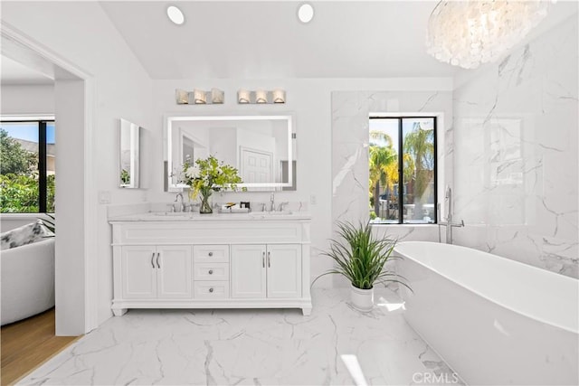 bathroom featuring double vanity, a freestanding tub, marble finish floor, and a sink