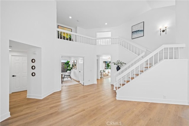 foyer entrance featuring wood finished floors, recessed lighting, stairway, a high ceiling, and baseboards