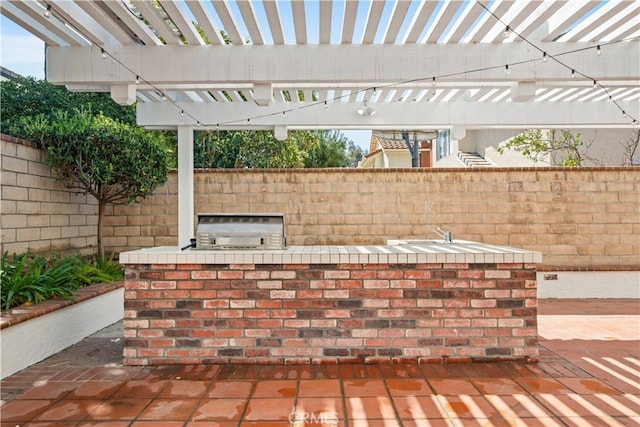 view of patio / terrace with an outdoor kitchen, a pergola, and fence