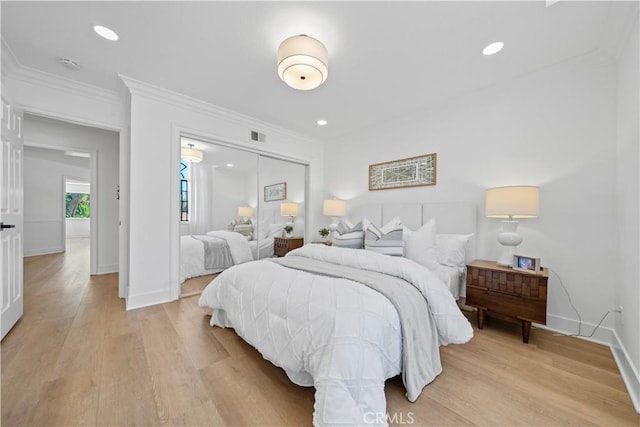 bedroom with a closet, light wood-style floors, and ornamental molding