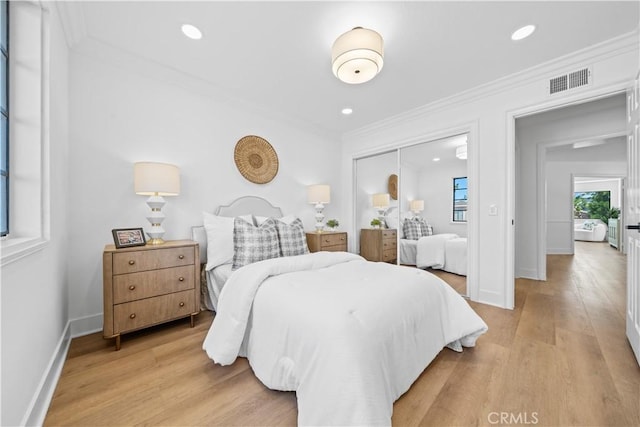 bedroom featuring crown molding, a closet, visible vents, and light wood finished floors