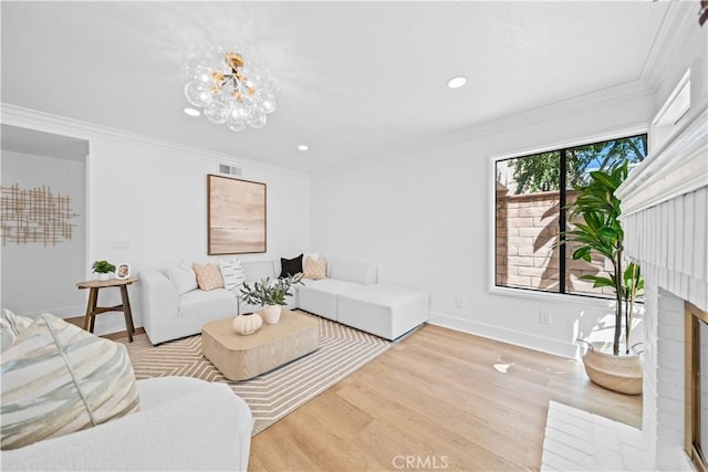 living area with wood finished floors, visible vents, a fireplace, ornamental molding, and a notable chandelier