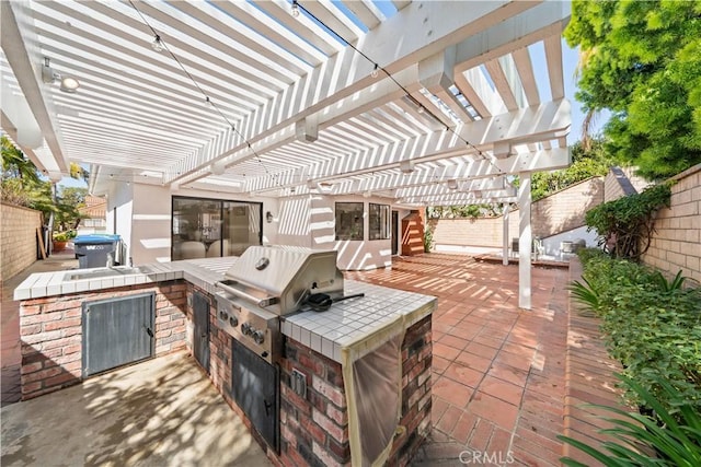 view of patio / terrace with area for grilling, a fenced backyard, a pergola, and exterior kitchen