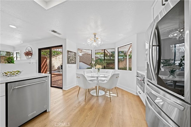 dining room featuring visible vents, baseboards, a chandelier, light wood-style flooring, and a textured ceiling