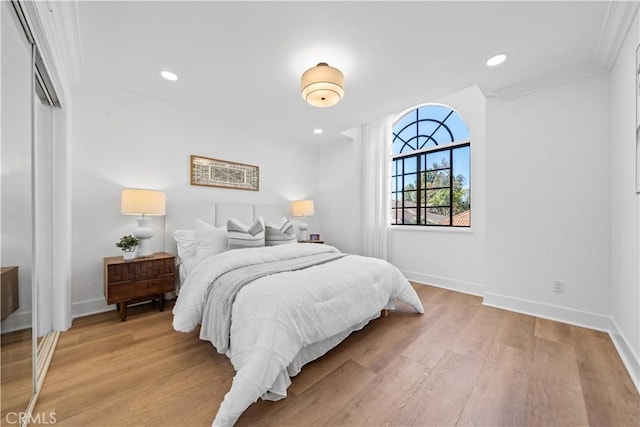 bedroom with recessed lighting, light wood-type flooring, baseboards, and ornamental molding