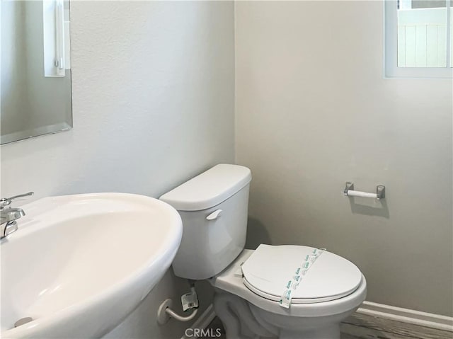 bathroom with toilet, baseboards, and a sink