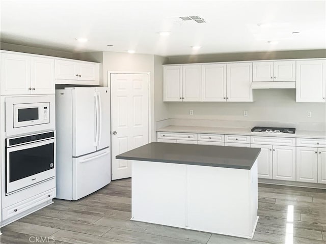 kitchen featuring white appliances, white cabinetry, and light wood finished floors