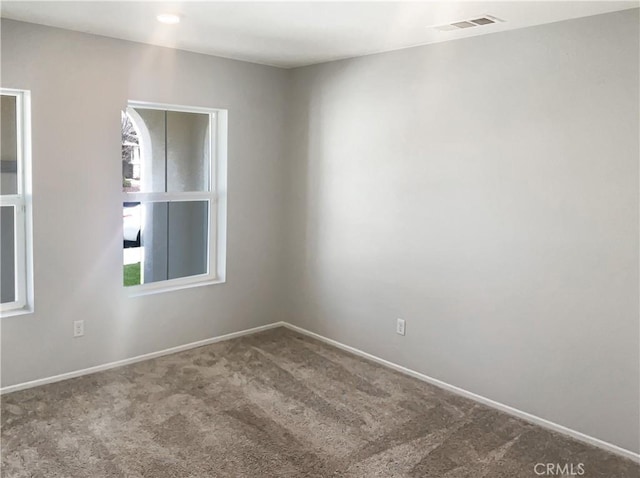 empty room featuring visible vents, baseboards, and carpet