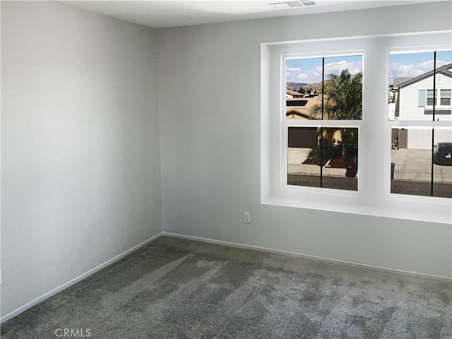 spare room with carpet flooring, baseboards, and visible vents