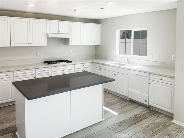 kitchen featuring under cabinet range hood, white cabinets, white appliances, and a sink