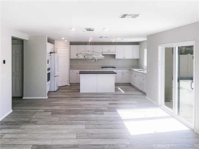 kitchen featuring light wood finished floors, visible vents, and white cabinetry