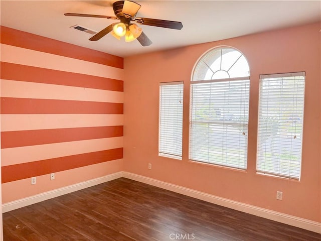 empty room featuring plenty of natural light, baseboards, and dark wood-style flooring