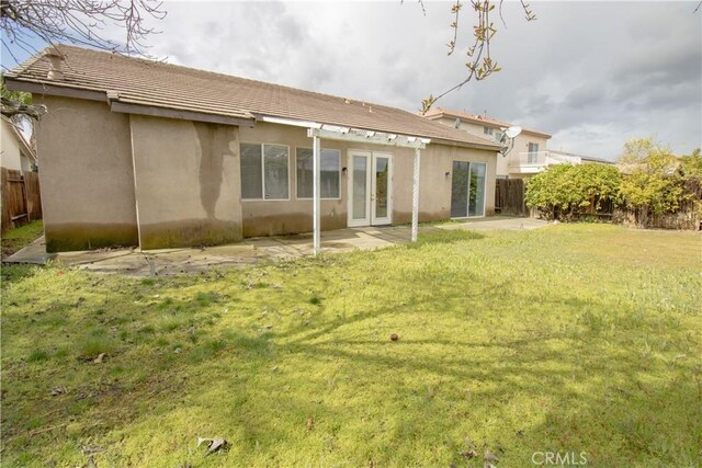 back of property with a patio, french doors, a yard, and fence