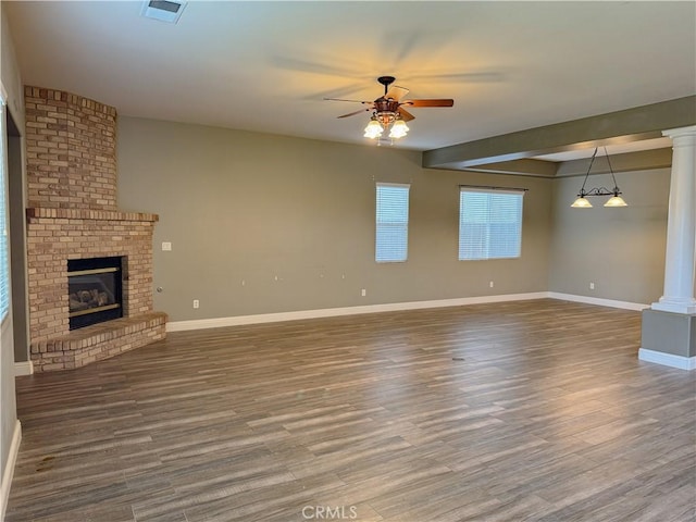 unfurnished living room with decorative columns, a ceiling fan, wood finished floors, and a fireplace