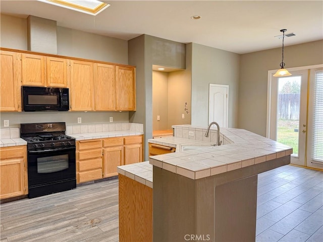 kitchen with visible vents, black appliances, light brown cabinets, a sink, and tile countertops