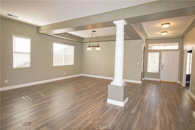 entrance foyer with visible vents, dark wood-type flooring, a raised ceiling, and ornate columns