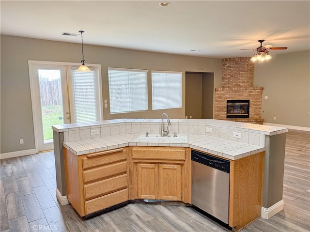 kitchen featuring tile counters, visible vents, dishwasher, and a sink