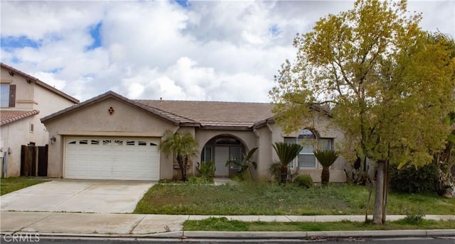 view of front facade with a tile roof, a garage, driveway, and stucco siding