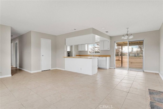 unfurnished living room with a textured ceiling, light tile patterned flooring, baseboards, and a chandelier