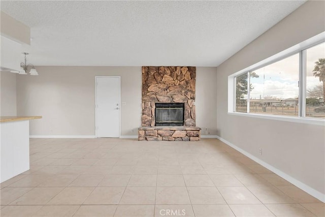 unfurnished living room with a stone fireplace, a notable chandelier, baseboards, and a textured ceiling