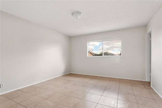 unfurnished room with light tile patterned floors, baseboards, and a textured ceiling