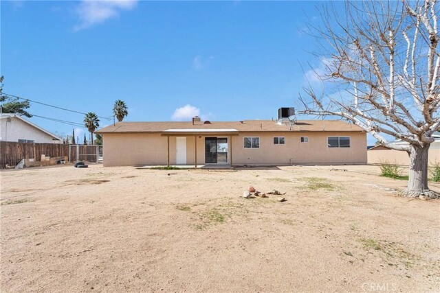 rear view of property with stucco siding, cooling unit, and fence