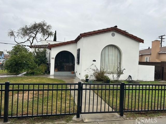 mediterranean / spanish-style house with stucco siding, a fenced front yard, a front yard, and a tile roof